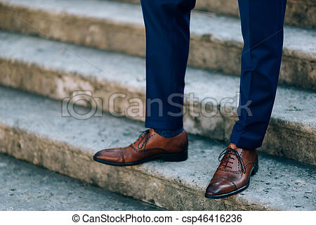 Brown shoes on male legs. the groom in a blue pant